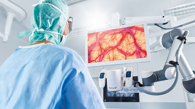 Chirurgo in sala operatoria con piattaforma per microscopio chirurgico digitale Aeos® Aesculap
