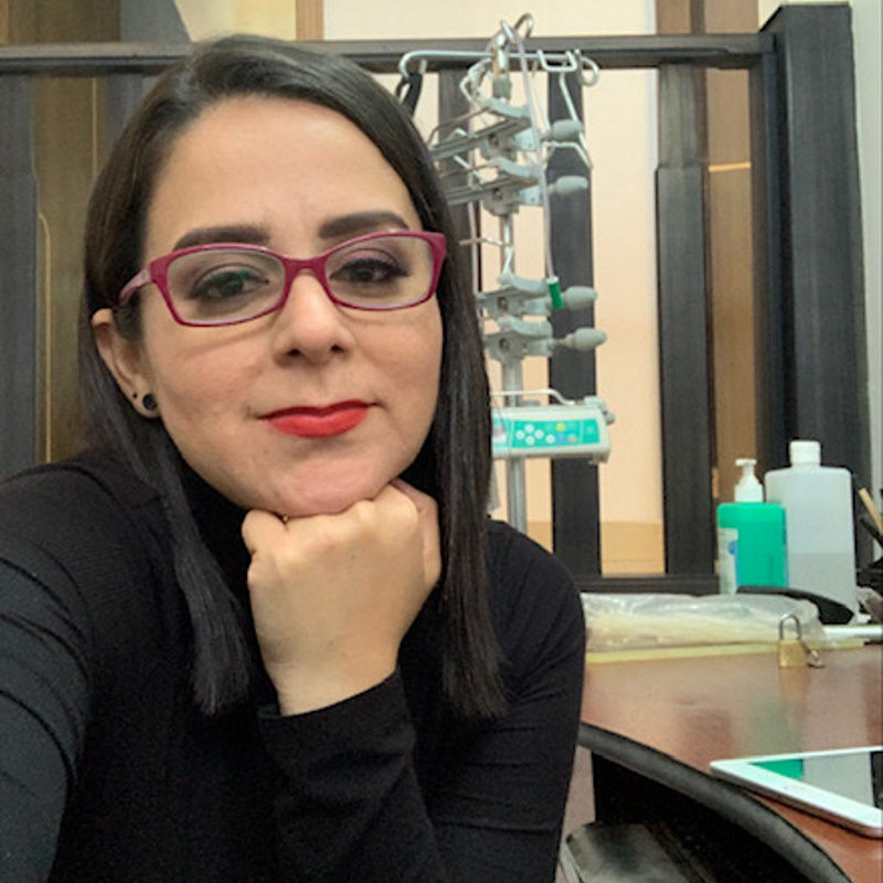 donna con capelli scuri, occhiali e rossetto appoggia la testa sulla mano