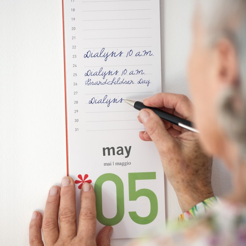 Una donna anziana prende appunti nel calendario