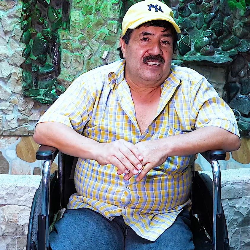 Uomo di Ecuador con berretto su sedia a rotelle